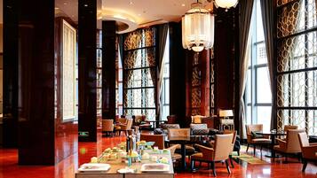 Un amplio vestíbulo de hotel con techos altos, ventanas grandes y elegantes candelabros.