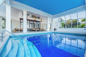 Una piscina techada, sillones reclinables de piscina