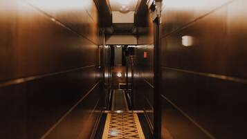 Vista del interior de un hueco de ascensor, con suelo estampado y paredes metálicas.