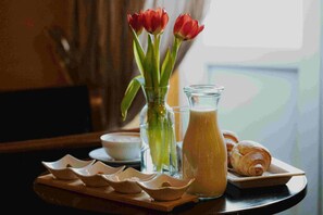 A breakfast tray with croissants, a glass pitcher of milk, and a vase with red tulips. - Historic Boutique Hotel Cattaro (Kotor)