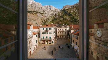 Un patio con edificios, un reloj y montañas al fondo.