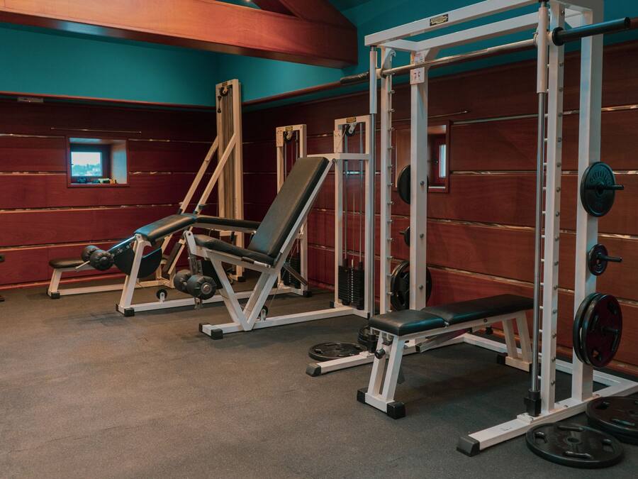 A gym with weightlifting equipment, benches, and a mirror.