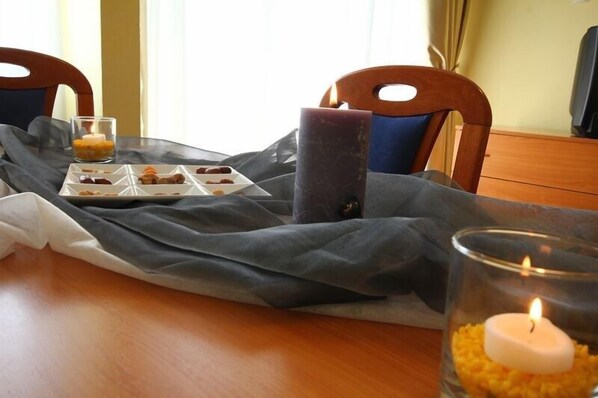 Una mesa de comedor con una vela, un vaso de agua y un plato de comida.