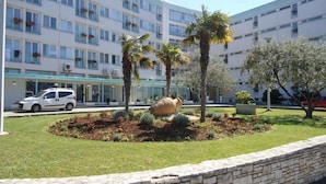 A modern hotel with a central courtyard featuring palm trees, a stone wall, and a large decorative rock.