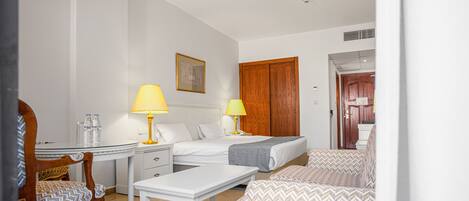 Quarto de hotel com uma cama, duas mesas de cabeceira, uma escrivaninha, uma cadeira e um sofá.