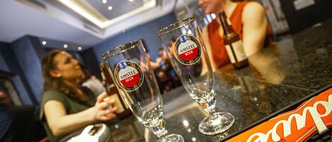 Two glasses of Amstel beer on a bar counter with a person in the background.