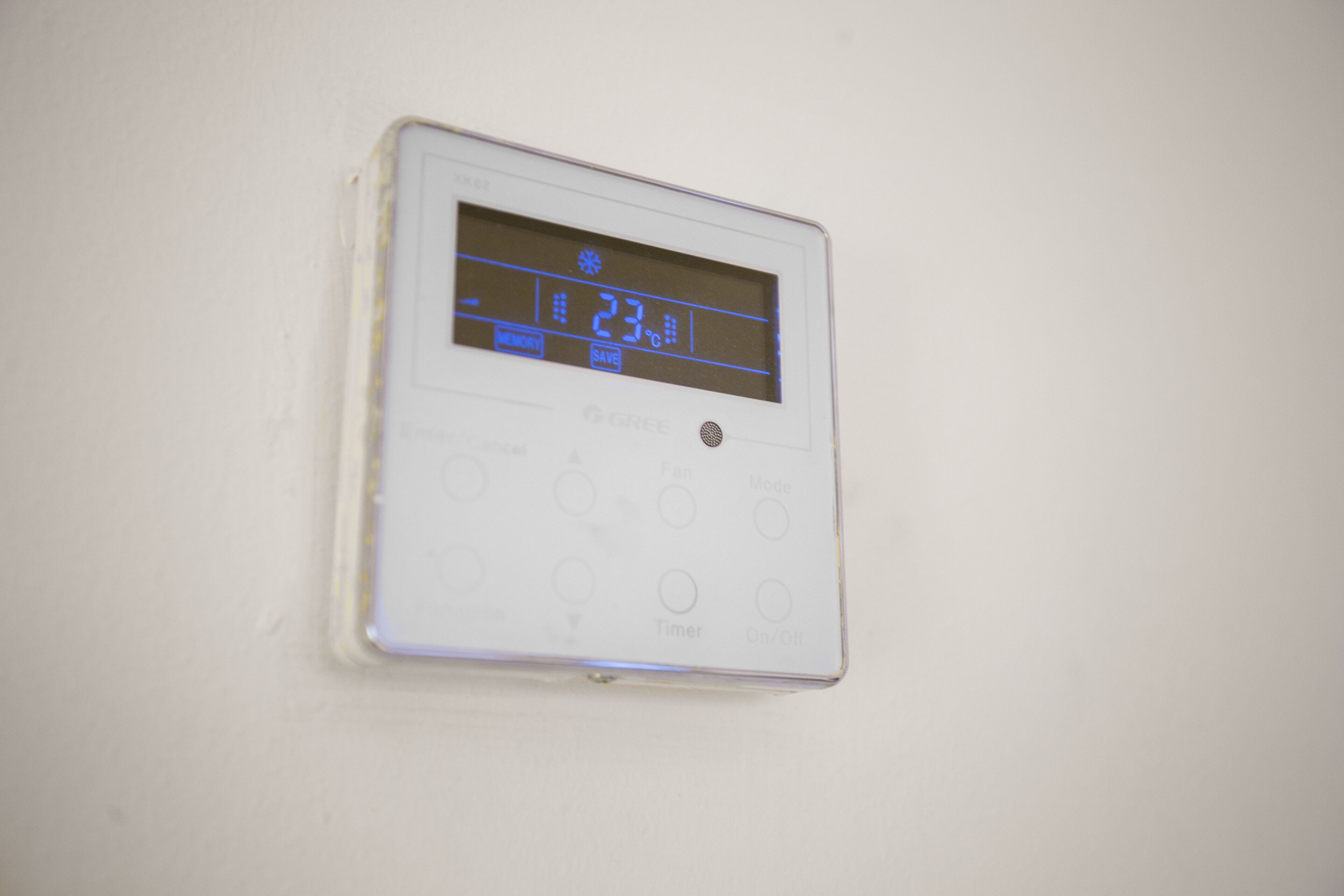 Ein digitales Thermostat an einer weißen Wand.