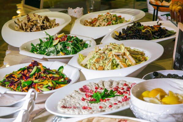 A variety of dishes on a table, including salads, meats, and a dessert. - Grand Hotel Madaba (Madaba)