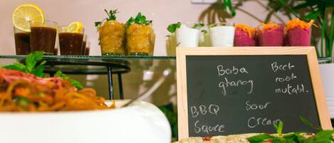 A buffet table with various dishes and a chalkboard menu listing options like BBQ sauce and cream.