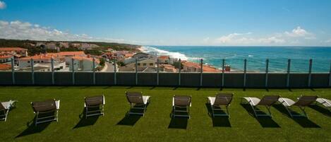 A terrace with sun loungers overlooking a coastal town.