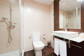 A modern bathroom with a glass shower enclosure, a white toilet, and a glass sink with a wooden panel backsplash. - Hotel Mar e Sol & Spa (Marinha Grande)
