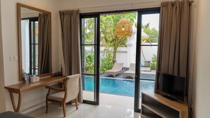 A bedroom with a large window, a desk, a chair, a TV, and a view of an outdoor swimming pool. - Awila Villa Kuta (Kuta)