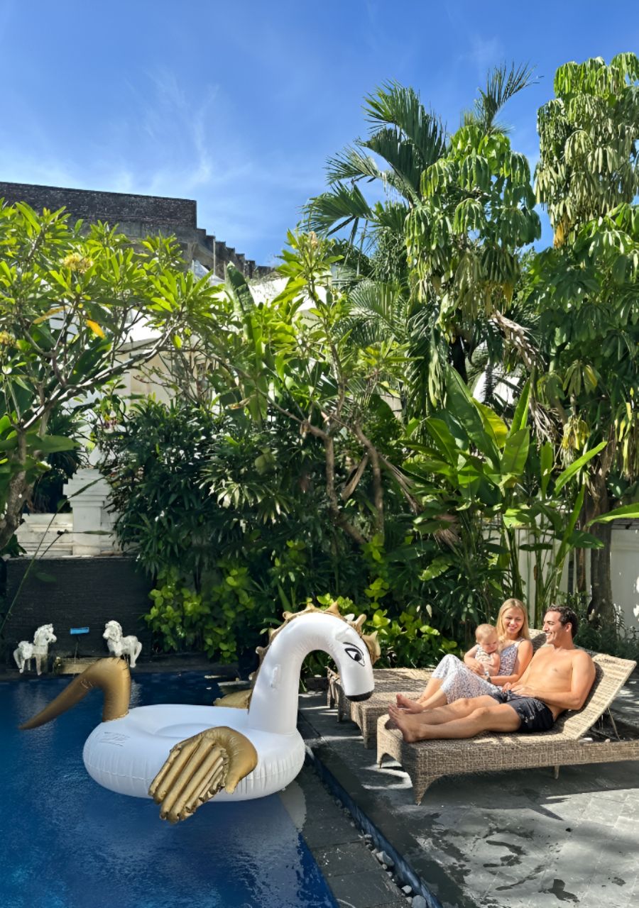 A pool area with a swan inflatable, lounge chairs, and lush greenery.