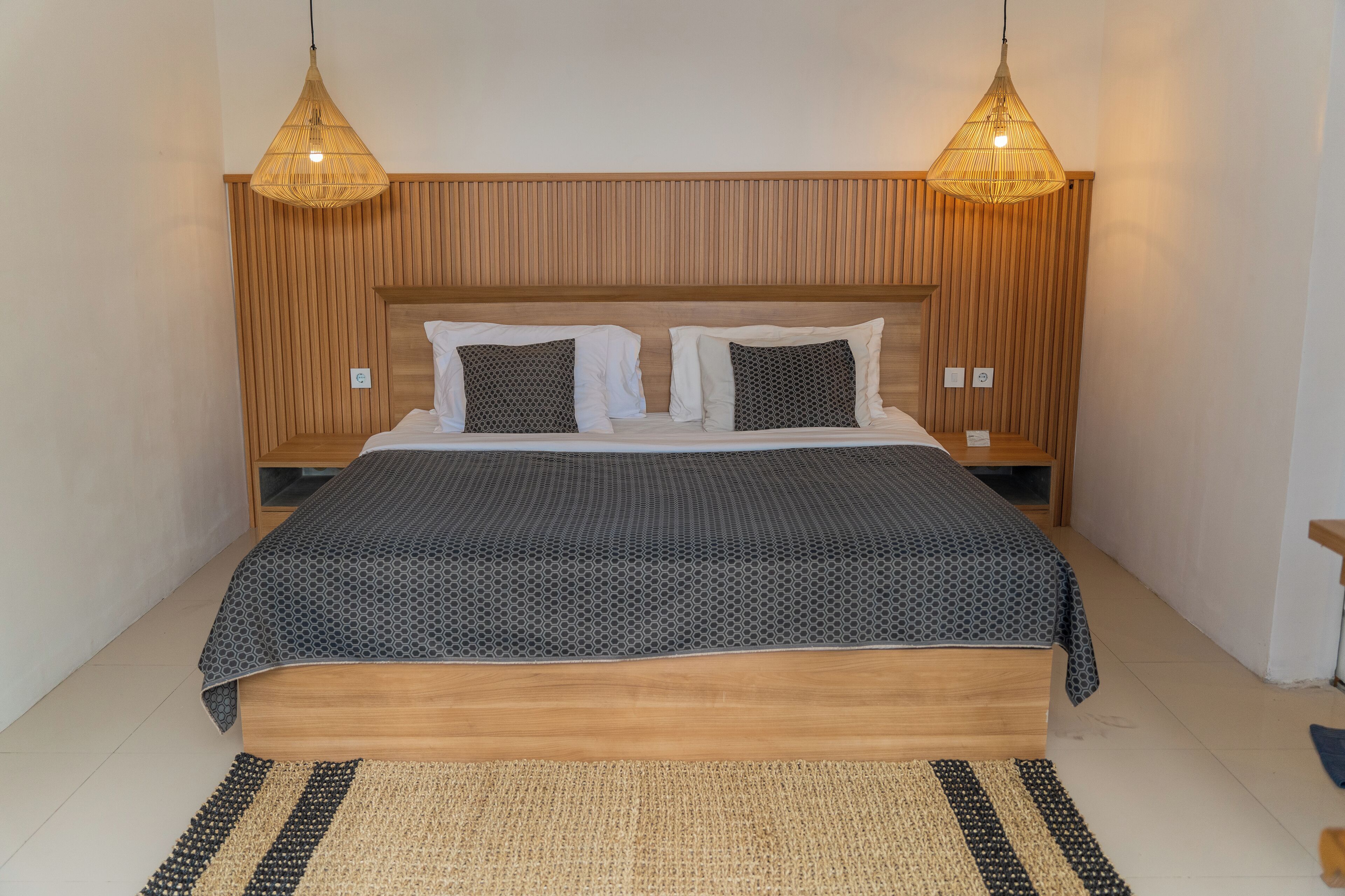 A bed with a wooden headboard, two bedside tables, and a patterned bedspread.
