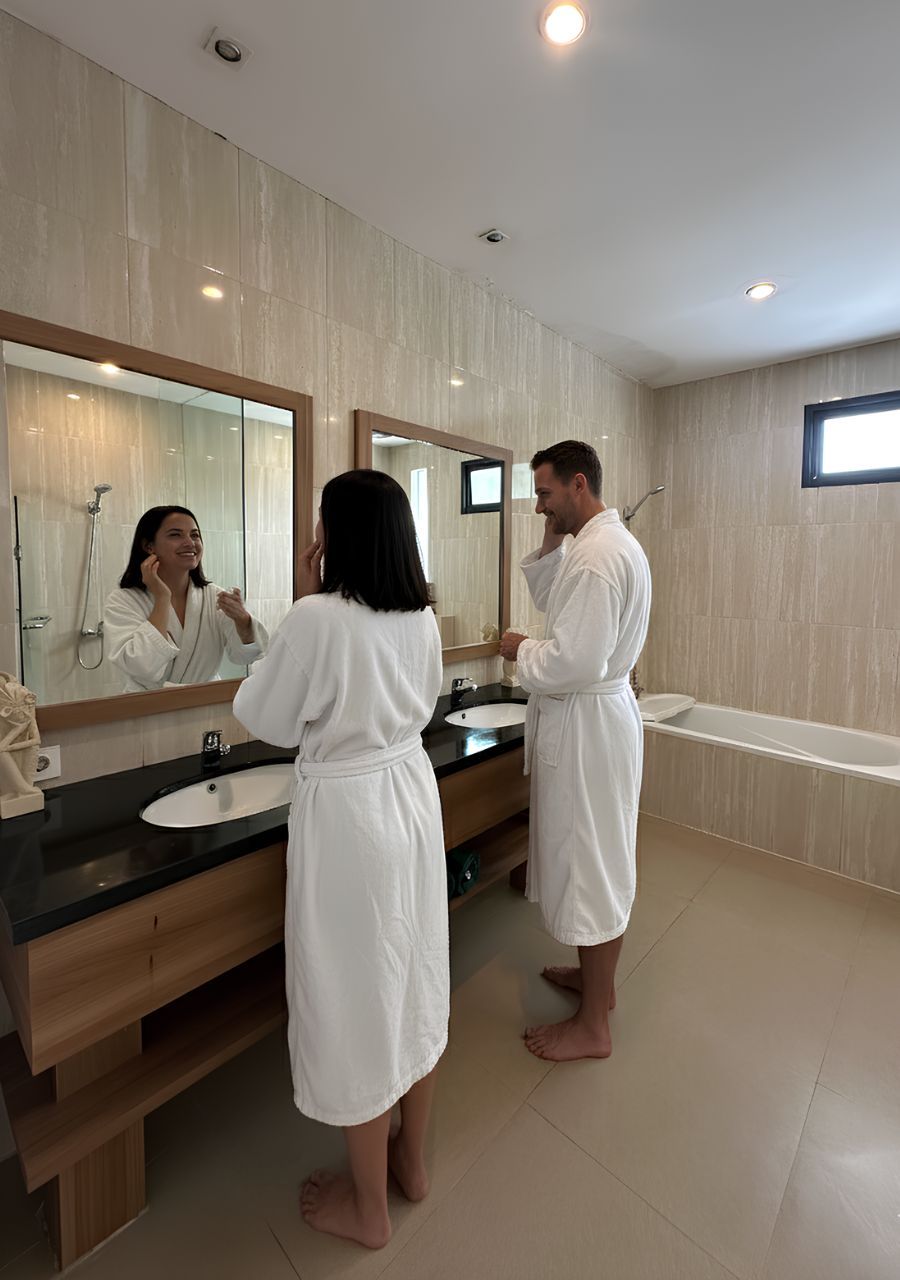 Un baño moderno con un espejo grande, un lavamanos y una bañera.