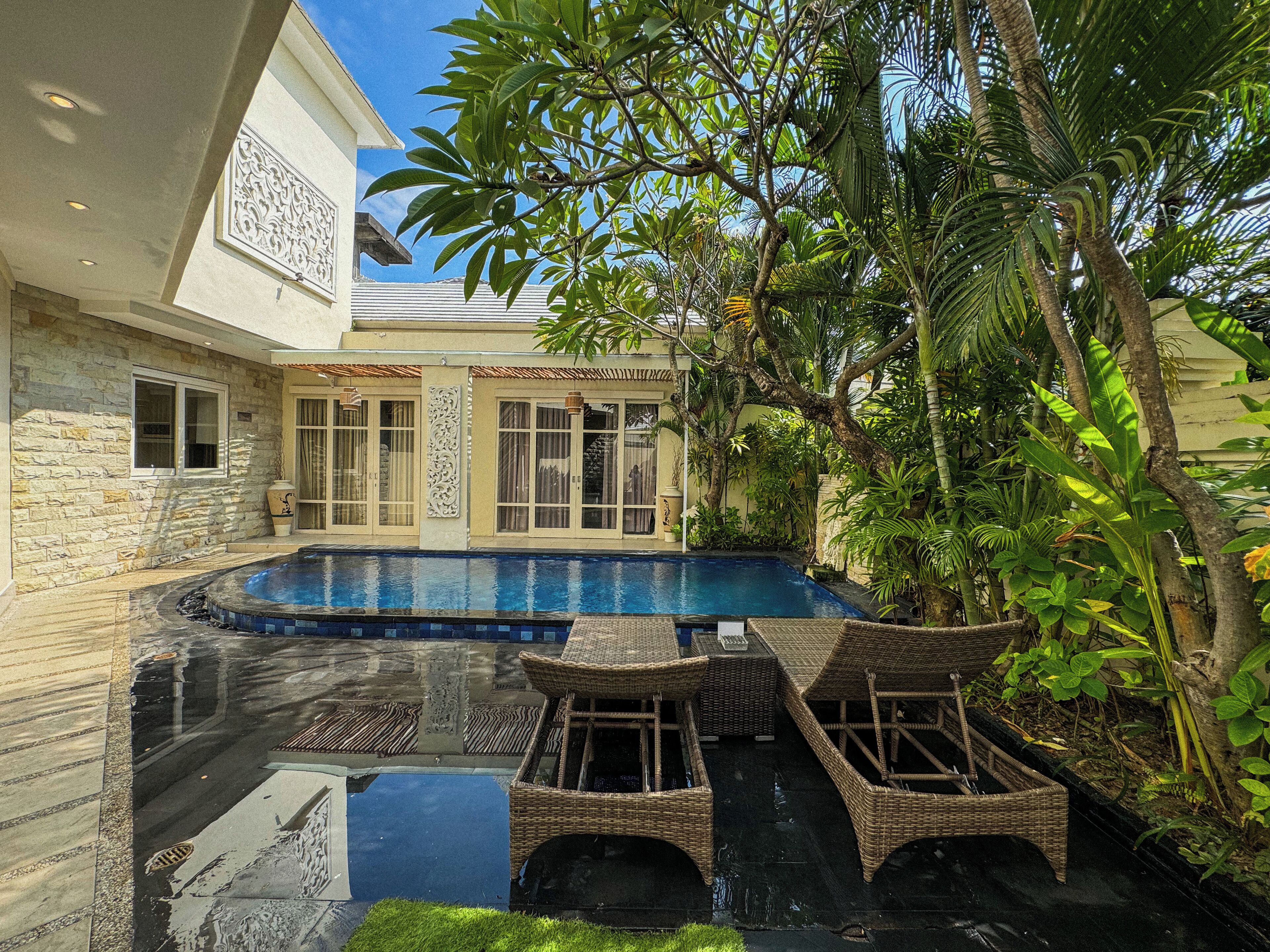 A swimming pool surrounded by lush greenery and a stone wall.
