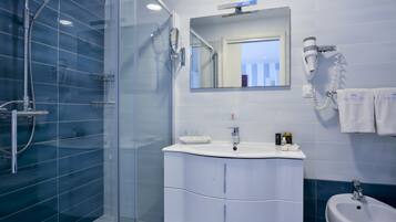A modern bathroom with a glass-enclosed shower, a white vanity with a mirror, and a sink.