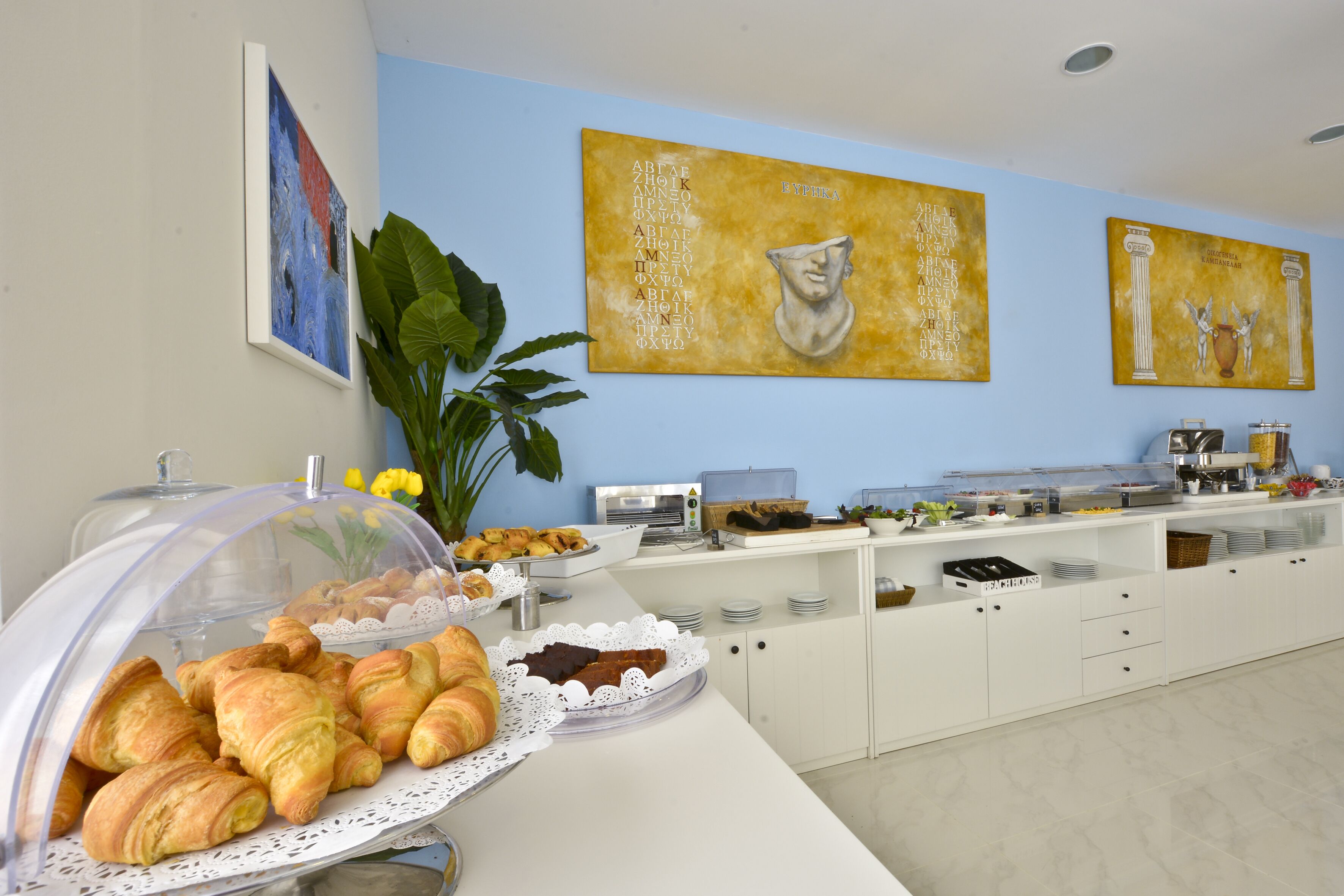 A breakfast buffet with croissants, pastries, and a coffee station.