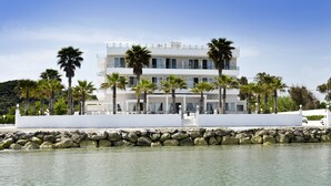 A modern building with a white facade, multiple balconies, and palm trees in front. - Sidari Beach Hotel (Corfu)