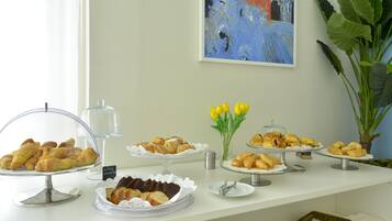 A buffet table with various pastries and a vase of yellow tulips.