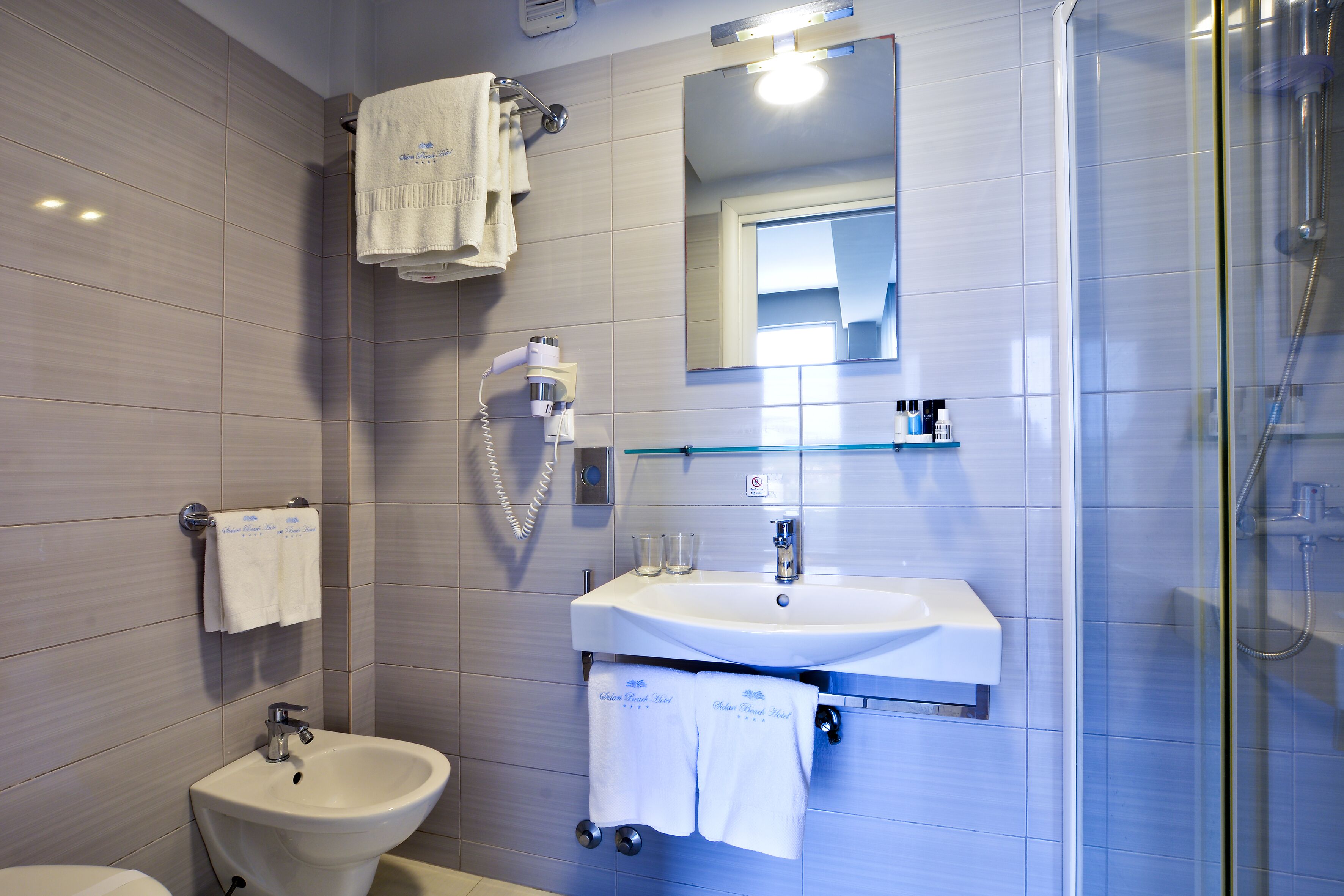 A modern bathroom with a bidet, sink, and glass-enclosed shower.