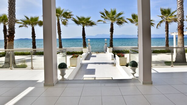 A corridor with palm trees and a view of the sea. - Sidari Beach Hotel (Corfu)