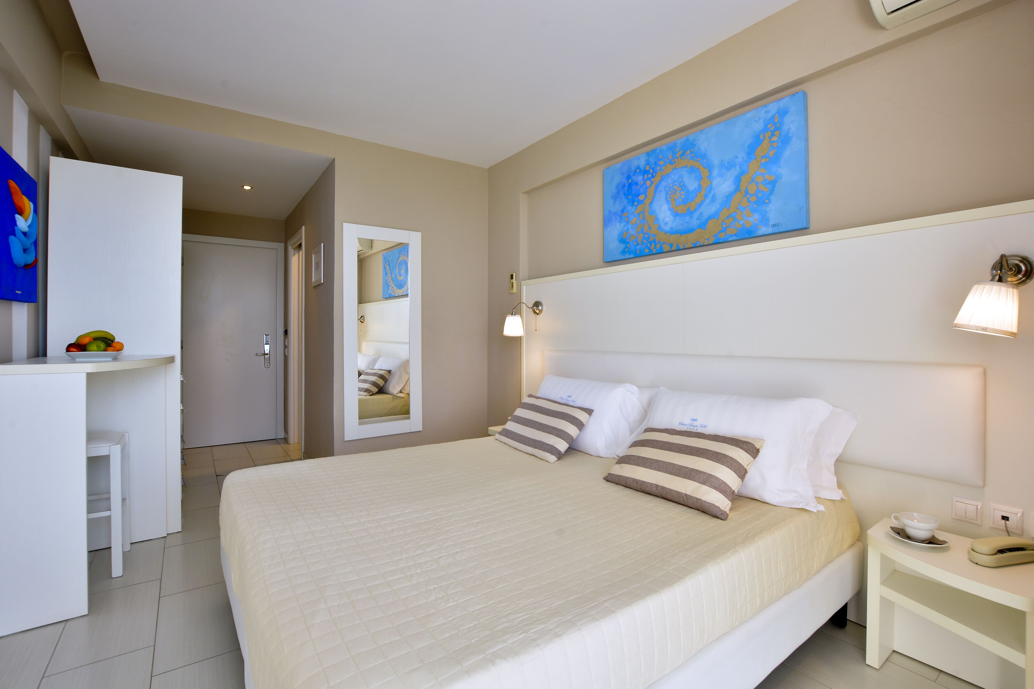 A hotel room with a bed, bedside table, and a desk area.