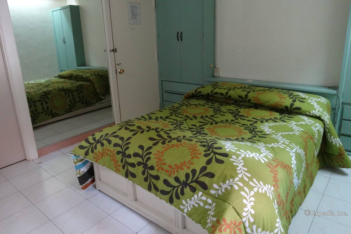 A bedroom with a bed, a wardrobe, and a mirror.