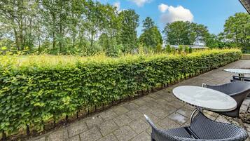 Relax in a serene garden setting with a patio featuring a pair of wicker tables and chairs.