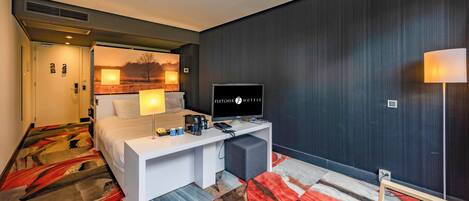 A hotel room with a bed, desk, television, and a view of the outdoors.