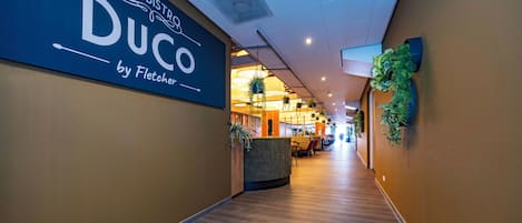 A hotel corridor with a sign for 'Duco by Fletcher' and a reception desk.