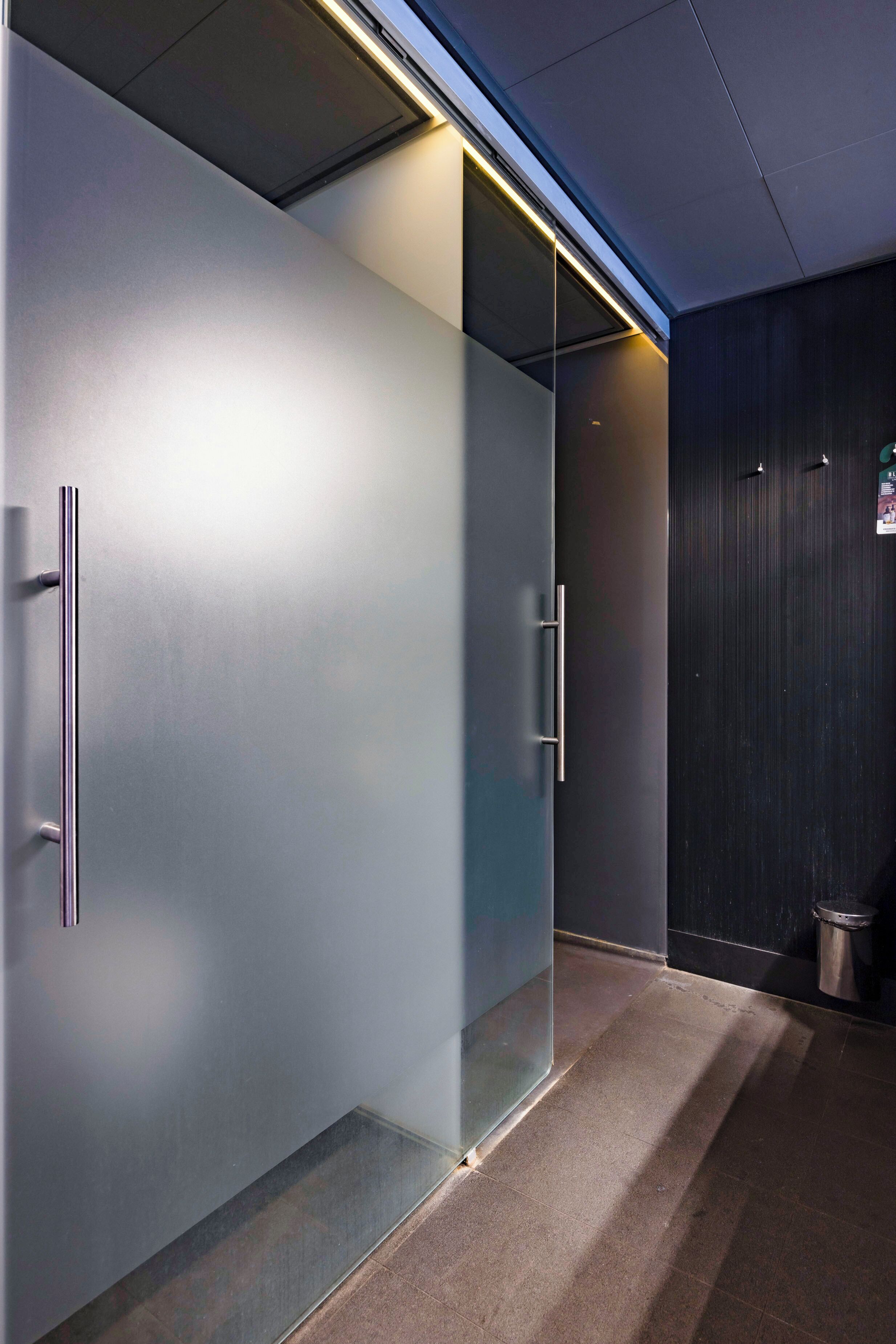 A modern hallway with frosted glass doors and a dark wall.
