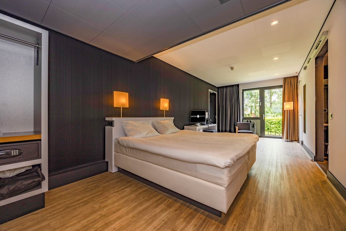Een moderne hotelkamer met een groot bed, nachtlampen, een bureau en een televisie.