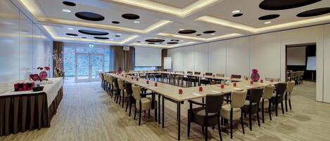 A conference room with a long table, chairs, and a projector screen.