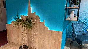 A room with a wooden partition, a potted plant, a blue chair, and a shelf with decorative items.