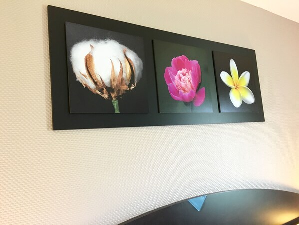 A wall-mounted art piece with three framed floral paintings.