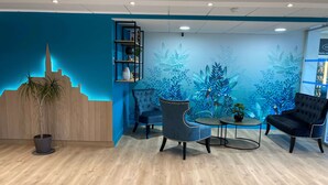 A modern reception area with a blue-themed mural, wooden reception desk, and seating arrangement.