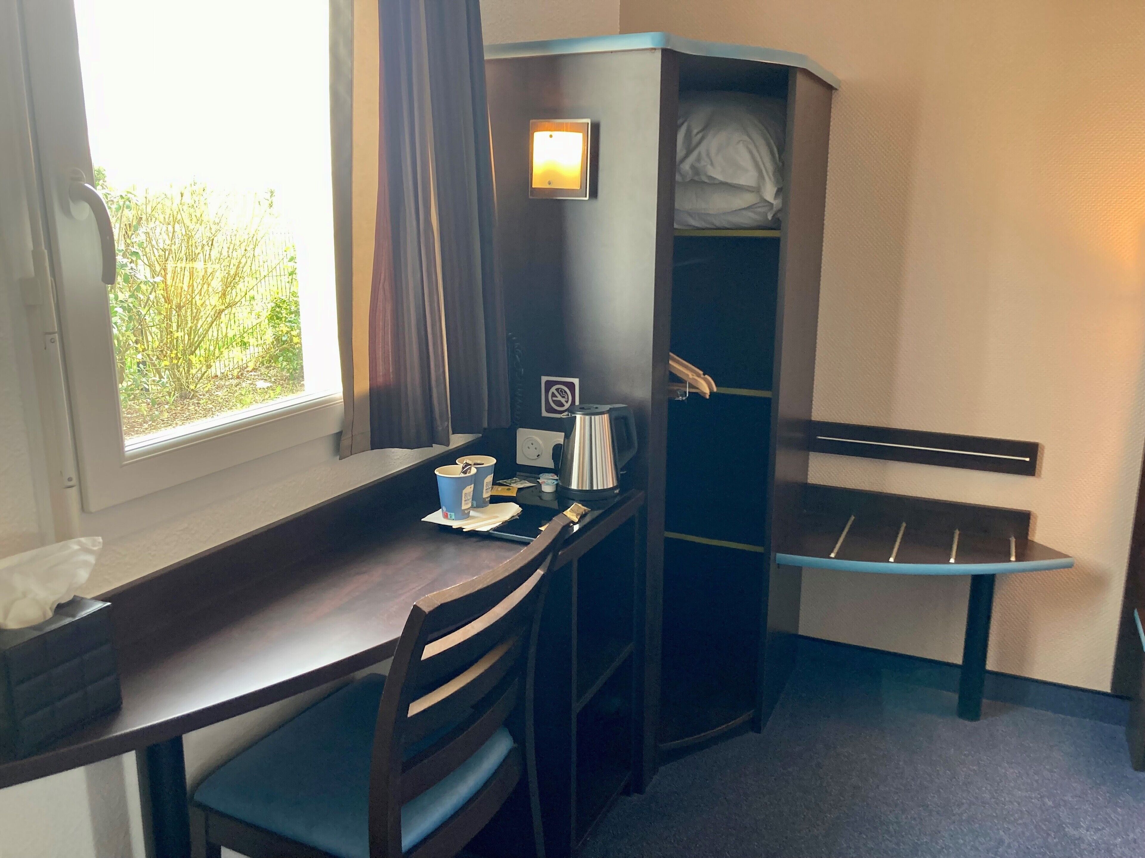 A compact room with a desk, chair, and a built-in wardrobe.