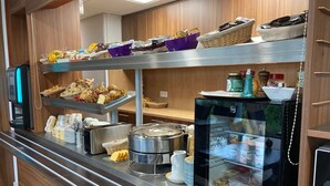 A buffet setup with various food items, a refrigerator, and a coffee machine.