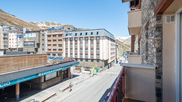 A hotel with a stone facade, a covered outdoor area, and a view of a street with a bus.