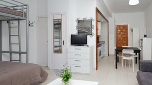 A compact living space with a bunk bed, a small kitchenette, a dining area, and a television.