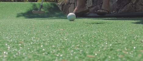 A golf ball on a green with a putter nearby.