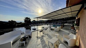 Una piscina al aire libre, sombrillas, sillones reclinables de piscina