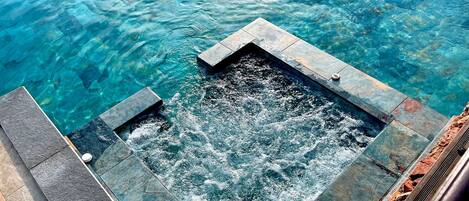 A hot tub with clear water, surrounded by stone steps.