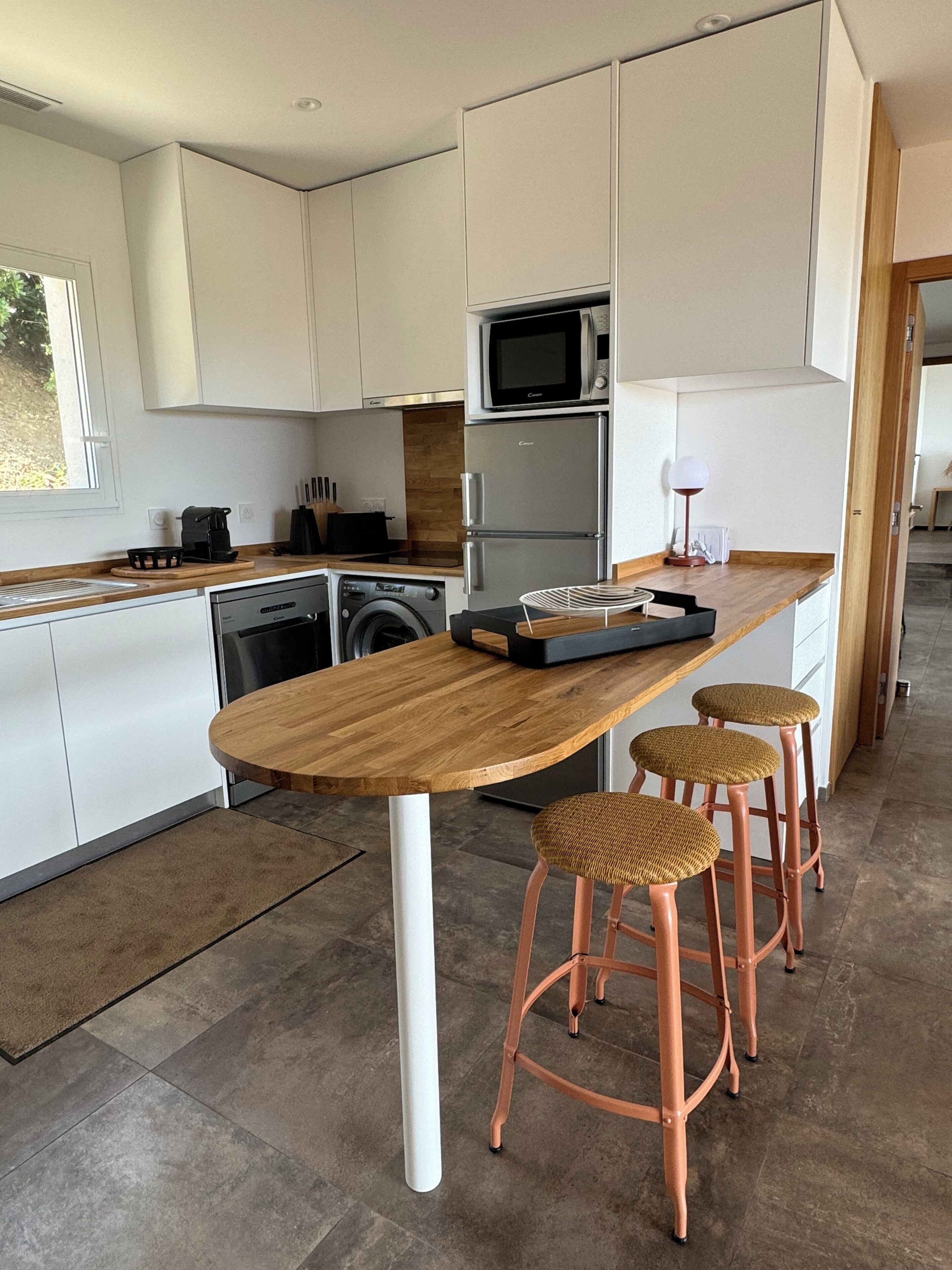 A modern kitchen with a wooden island, stainless steel appliances, and a view into the dining area.