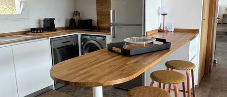 A modern kitchen with a wooden island, stainless steel appliances, and a view into the dining area.
