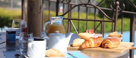 A table set with a white mug, a glass of water, a teapot, croissants, and a jug of juice.