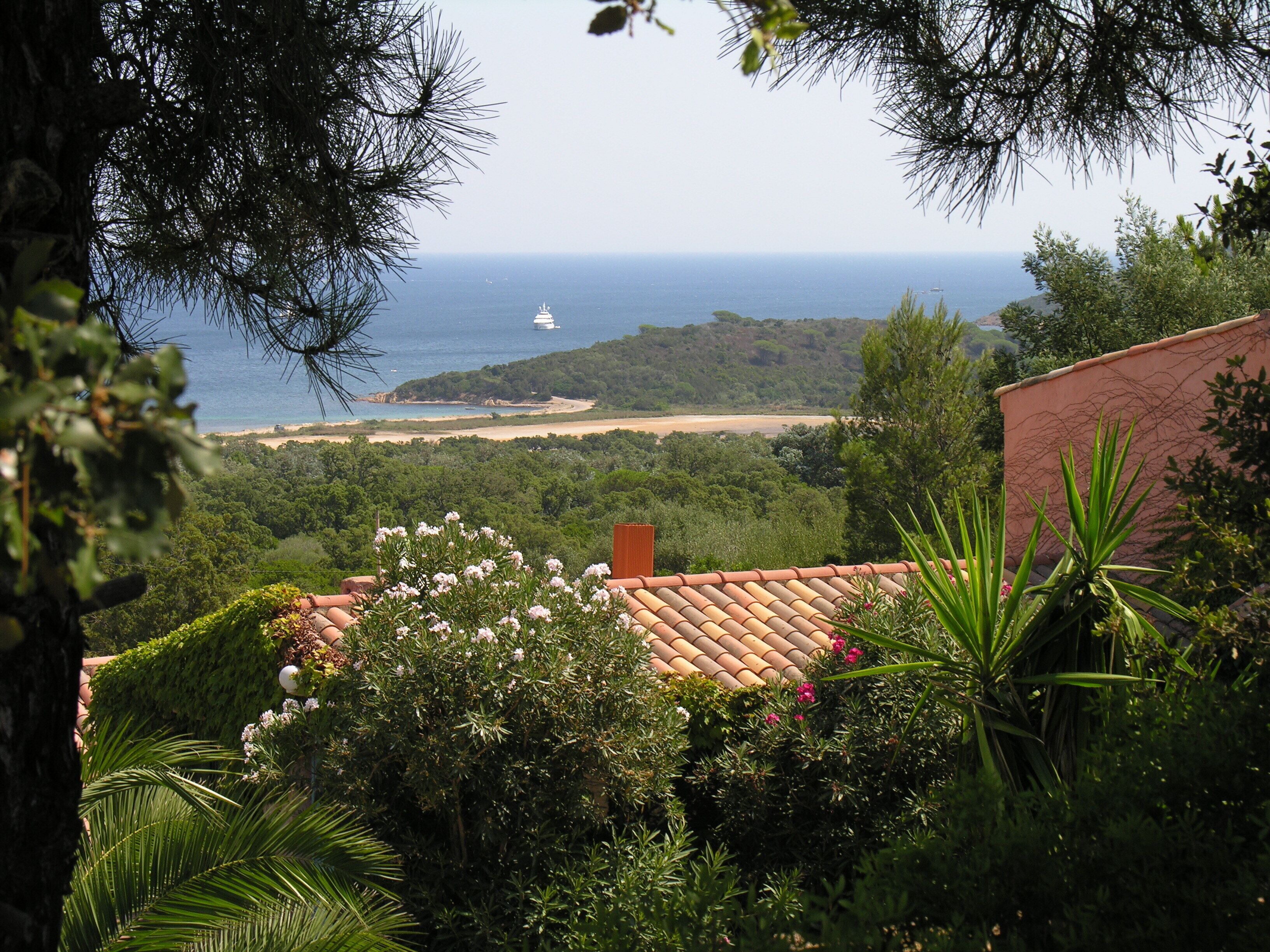A coastal view with a beach, a boat, and dense greenery.