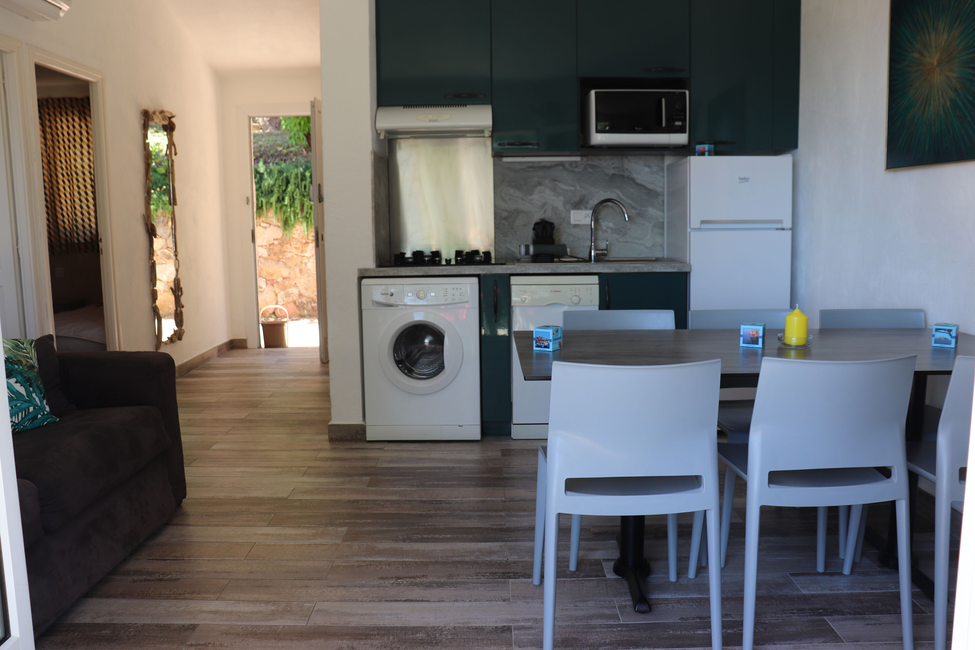 A compact living space with a kitchen, a dining area with two chairs, a sofa, and a washing machine.