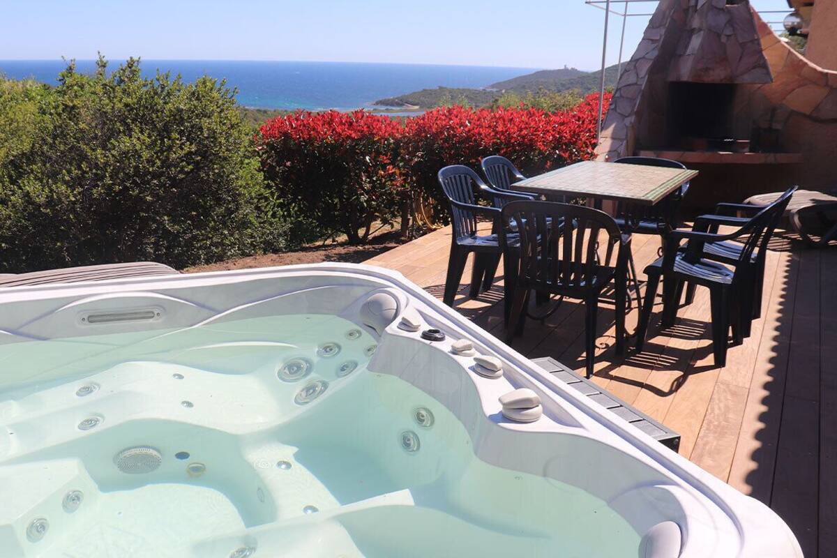 Ein Whirlpool mit Meerblick, umgeben von Gartenmöbeln und einer Steinstruktur.